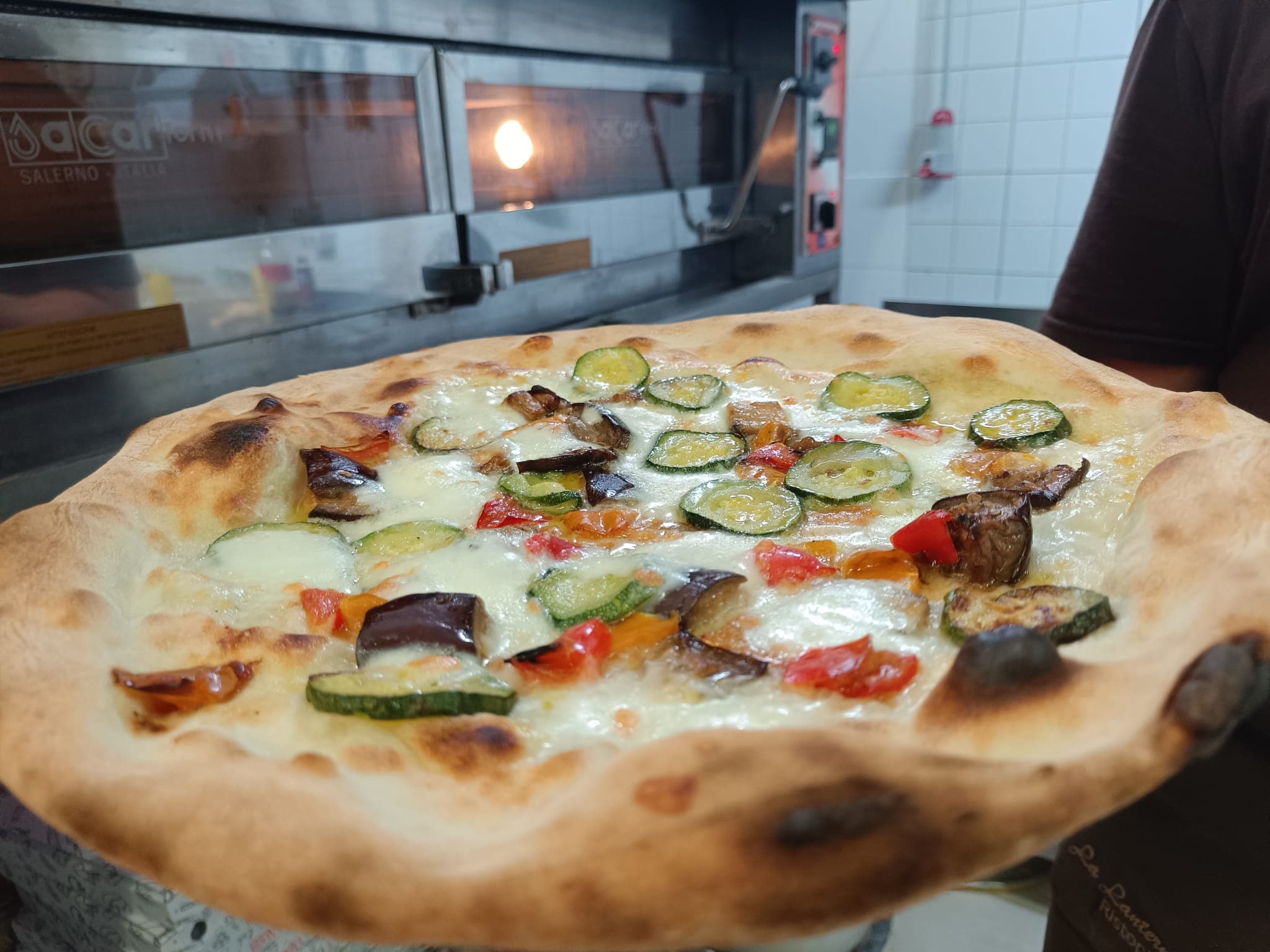 Pizza con verdure appena sfornata davanti al forno a legna de La Lanterna